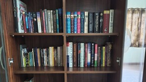 A wooden bookshelf with multiple shelves filled with books. - Charming & Spacious 2-bedroom apartment in amazing Bengaluru with WiFi, fitness. (Bengaluru)