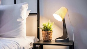 A neatly made bed with white linens, a small bedside table with a woven plant pot and a modern lamp, and a black metal headboard. - Waterfront house private jetty kayaks provided (Hindmarsh Island)