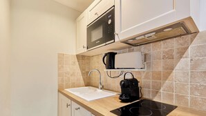A kitchen with a microwave, coffee maker, sink, and induction cooktop. - Apartement With AC Center of Paris (Paris)