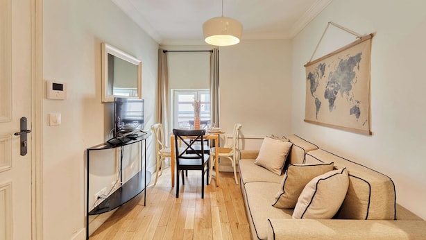 A modern living room with a sofa, a dining table, and a TV on a stand. - Apartement With AC Center of Paris (Paris)