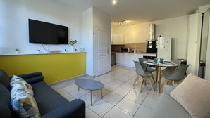 Una sala de estar moderna con un sofá, una mesita y un televisor montado en la pared.