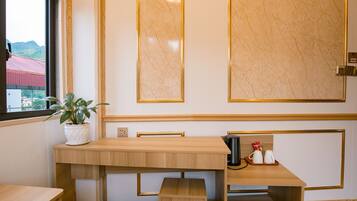 A wooden desk with a potted plant, a pair of shoes, and a coffee maker.
