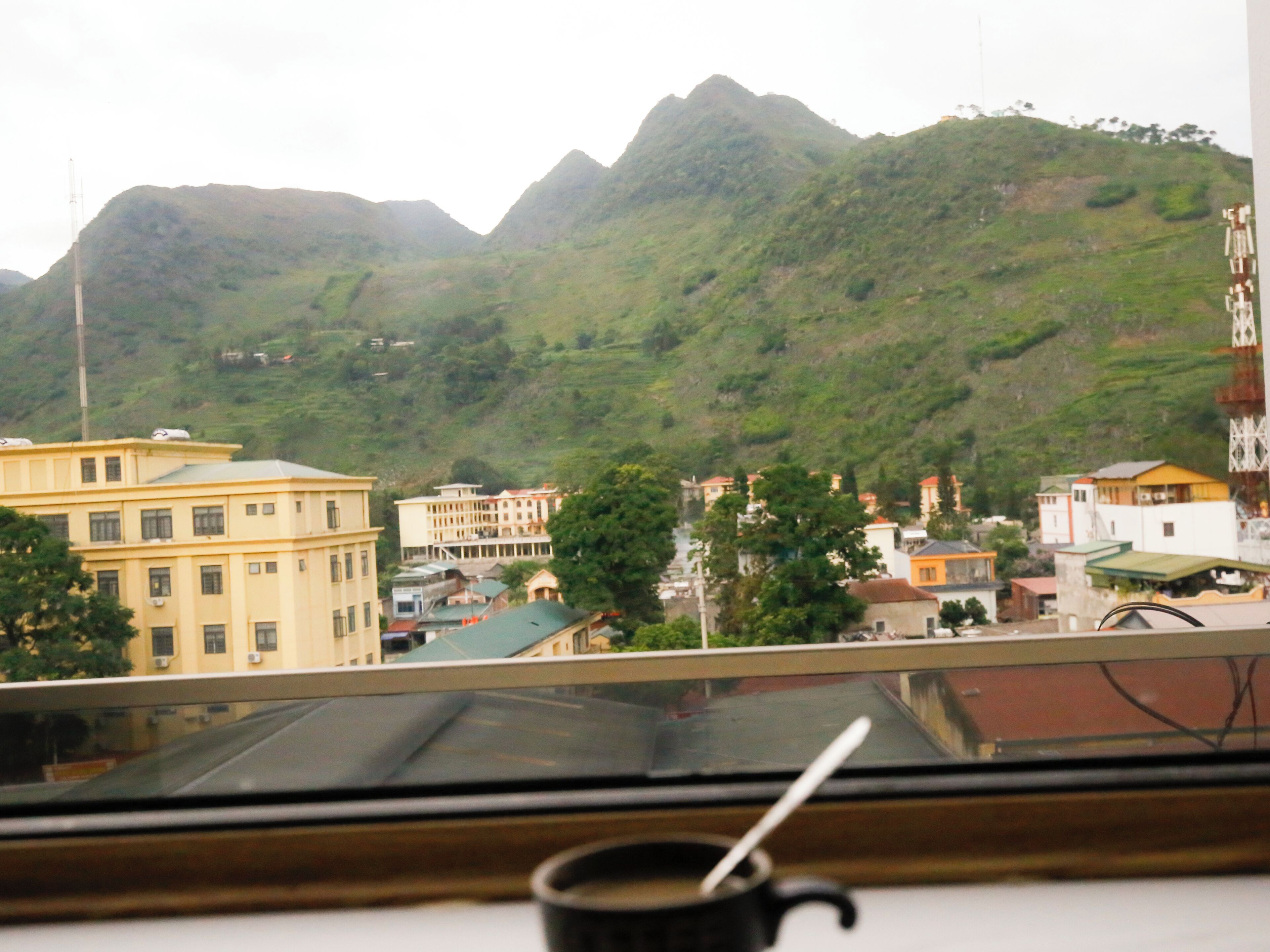 A view of a town with buildings and mountains in the background.