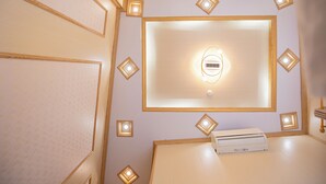 Una habitación con una lámpara en el techo, una unidad de ventilación y luces decorativas en la pared.