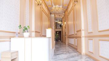 Un hall d’hôtel avec un sol en marbre, un comptoir d’accueil et un lustre.