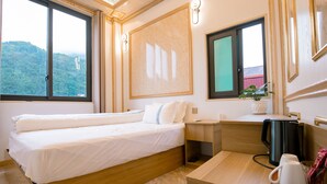 Habitación de hotel con cama, escritorio con hervidor, planta en maceta y vista a un paisaje montañoso.
