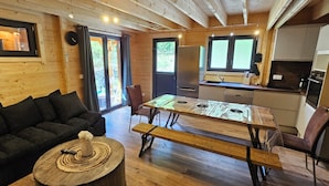 Un intérieur de chalet chaleureux avec un canapé, une table à manger en bois et un coin cuisine.