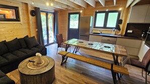 L’intérieur chaleureux d’un chalet comprend un canapé, une table ronde en bois, une table à manger et un coin cuisine.