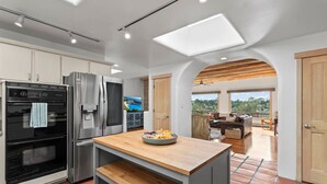 Una cucina moderna con elettrodomestici in acciaio inossidabile, un'isola in legno e vista su un balcone con posti a sedere all'aperto.