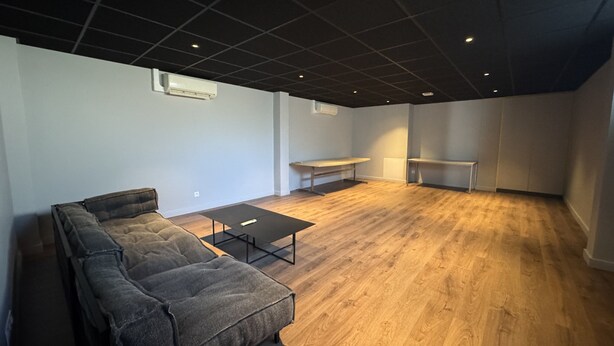 En rummelig stue med en stor hjørnesofa, et lille bord og en bænk.