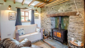 Un salón acogedor con chimenea de piedra, vigas de madera, un sofá y un sillón de cuero.