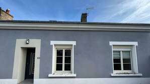 Ein zweistöckiges Gebäude mit grauer Fassade, weißen Fensterverzierungen und einem Eingang im Steinoptik.