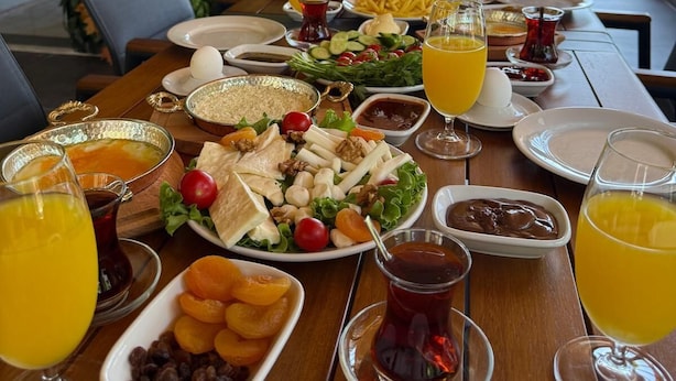 Een ontbijtbuffet met diverse gerechten, drankjes en uitzicht op groen.