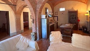 Une cuisine rustique avec des arches en briques, un réfrigérateur, un four à micro-ondes et une table à manger avec des chaises.
