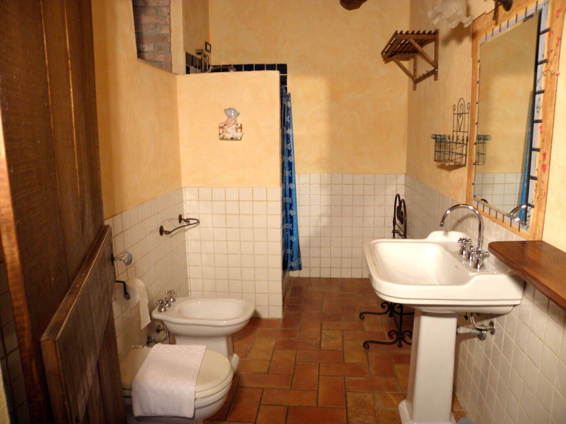 Une salle de bain équipée de toilettes, d’un bidet, d’un lavabo et d’un miroir.