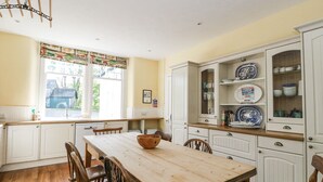 A kitchen with a wooden table, white cabinets, and a window with a view of the outside. - Camisky Lodge (Fort William)