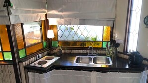 Cocina compacta con pileta, cocina y ventana con vitrales.