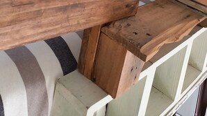 Un dormitorio con cabecera de cama de madera, almohadas a rayas y una pequeña mesita de noche con libros.