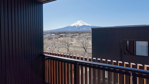 Vue d’une montagne enneigée depuis un balcon doté d’une balustrade en bois.