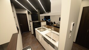 Une cuisine moderne équipée d’une cuisinière intégrée, d’un évier et d’un plan de travail. Une porte donne accès à une autre pièce et une fenêtre se trouve au-dessus de l’évier.