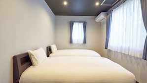 Une chambre d’hôtel moderne avec un grand lit, une fenêtre avec des rideaux et un climatiseur fixé au mur.
