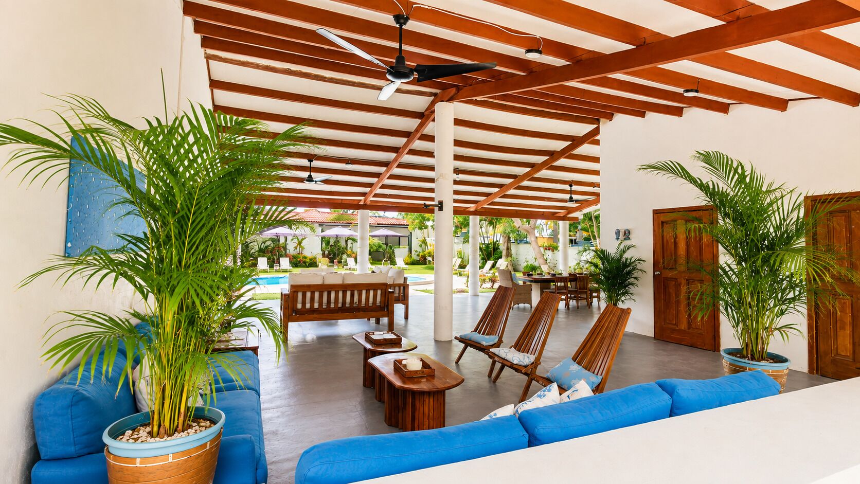 A spacious indoor area with a pool, wooden furniture, and potted plants.