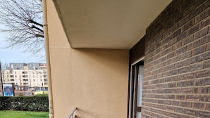 A balcony with a metal railing, a small table, and two chairs.