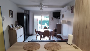 A dining area with a table and chairs, a ceiling fan, and a view of the outdoors.