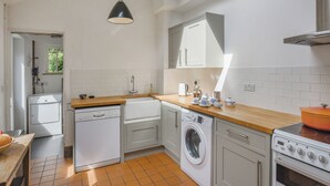 A compact kitchen with white cabinets, a washing machine, a dishwasher, and a stove.