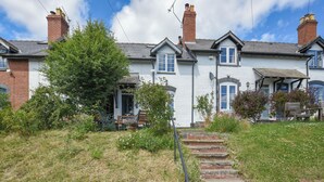 A two-story house with a front garden, a stone staircase, and a bench.