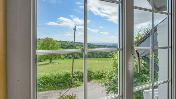 A window with a view of a green landscape and a clear sky.