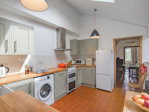 Une cuisine compacte équipée d’un lave-linge, d’un four à micro-ondes et d’une cuisinière.