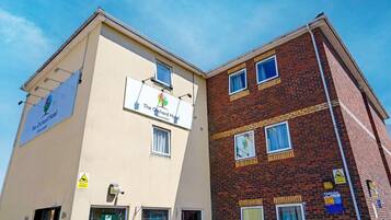 Two buildings, one with a sign for 'The Orchard Hotel' and another with a 'PARKING' sign.