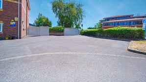 A parking lot with a brick building on the left and a modern building on the right. - GO2 Gloucester Hotel by OYO | Standard Double (Gloucester)