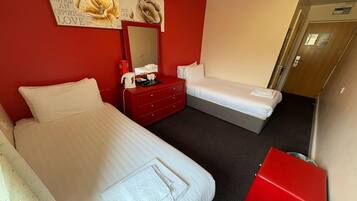A hotel room with two beds, a red dresser, a mirror, and a red cabinet.