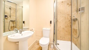 Ein Badezimmer mit Waschbecken, Toilette und einer behindertzugänglichen Duschkabine.