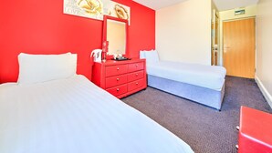 Ein Hotelzimmer mit zwei Betten, einer roten Kommode und einem großen Spiegel.