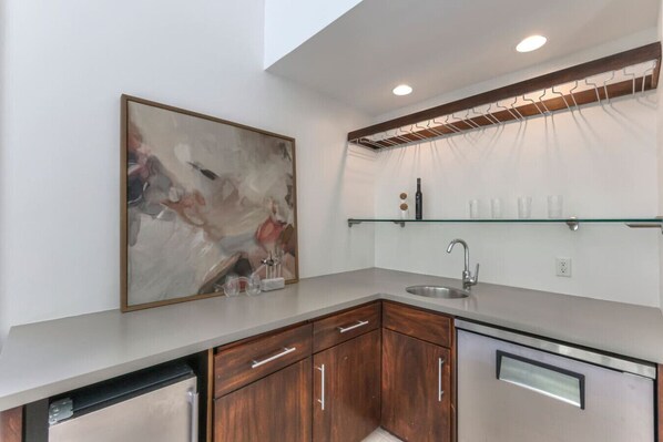 A modern kitchen with a stainless steel sink, wooden cabinets, and a glass shelf above the sink.