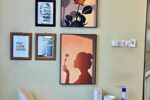 Un mur orné de tableaux encadrés, dont une silhouette d’une femme tenant une rose, une citation encadrée et une photographie encadrée d’une femme tenant un verre.