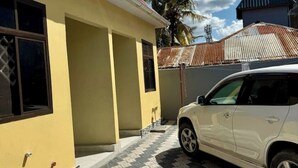 Un edificio amarillo con un coche blanco estacionado adelante.