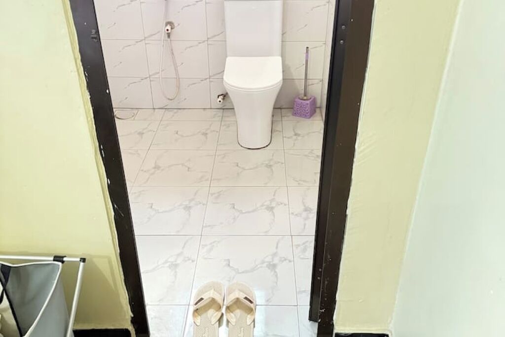 Une salle de bain avec des toilettes, une douche et une serpillière sur le sol.