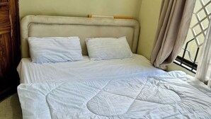 Una cama con cubrecolcha acolchado, dos almohadas y un cabecero de madera.