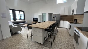 Une cuisine moderne dotée d’un îlot central, de tabourets de bar, d’une table à manger et d’un four encastré.