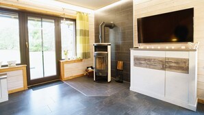 A modern kitchen with a built-in stove, a large flat-screen TV, and a sliding glass door leading to a patio. - Doppelhaushalfte mit Kamin in Hasselfelde (Oberharz am Brocken)