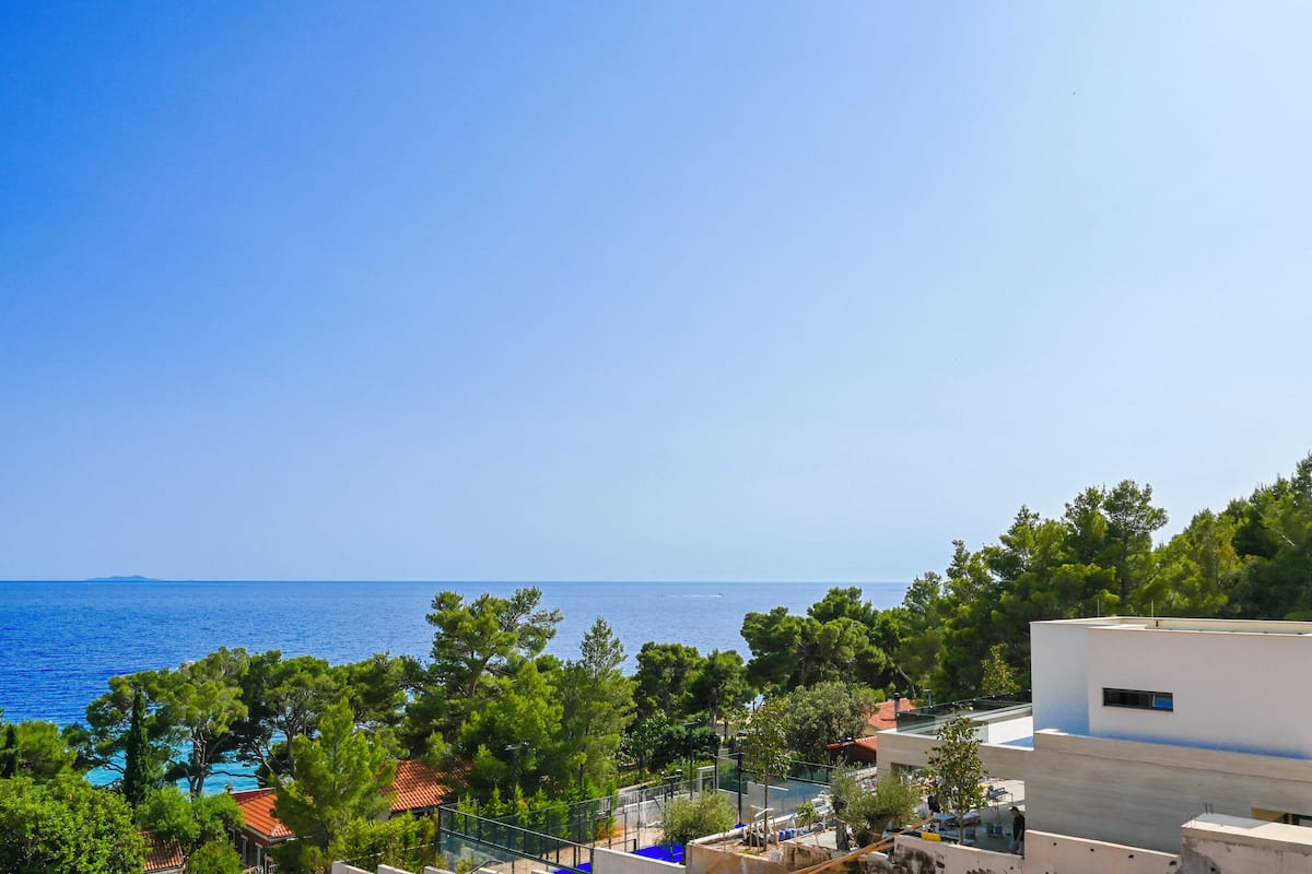 Une vue sur la côte, avec un ciel bleu dégagé, une piscine et de luxuriants arbres verdoyants.