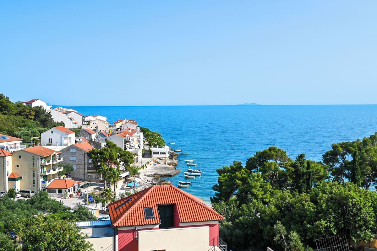 Une ville côtière avec des bâtiments, une mer bleue et limpide, et des bateaux.