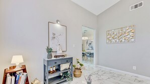 Een modern interieur met een console tafel, een lamp, een boekenkast en een decoratief wandobject.