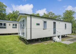 A mobile home with a front door, a small window, and a ramp leading to the entrance.