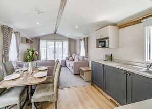 A modern kitchen with a microwave, a sink, and a dining area with a table set for four.