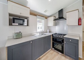 A modern kitchen with a microwave, toaster, sink, stove, and oven.